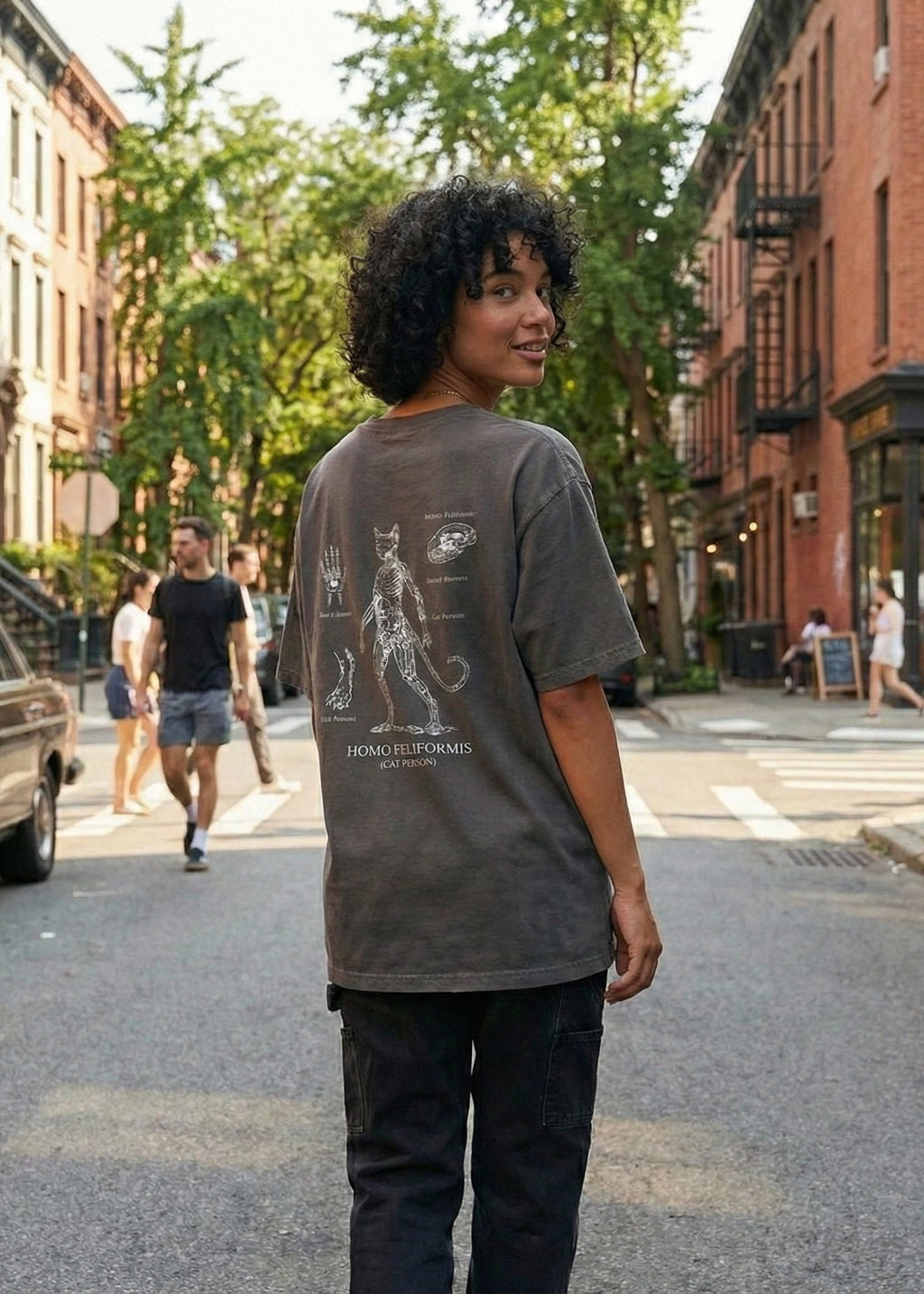Person wearing a gray t-shirt with a graphic design on a city street.