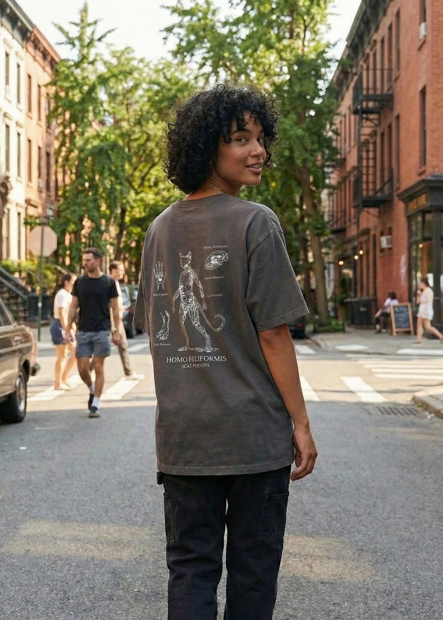 Person wearing a gray t-shirt with a graphic design on a city street.