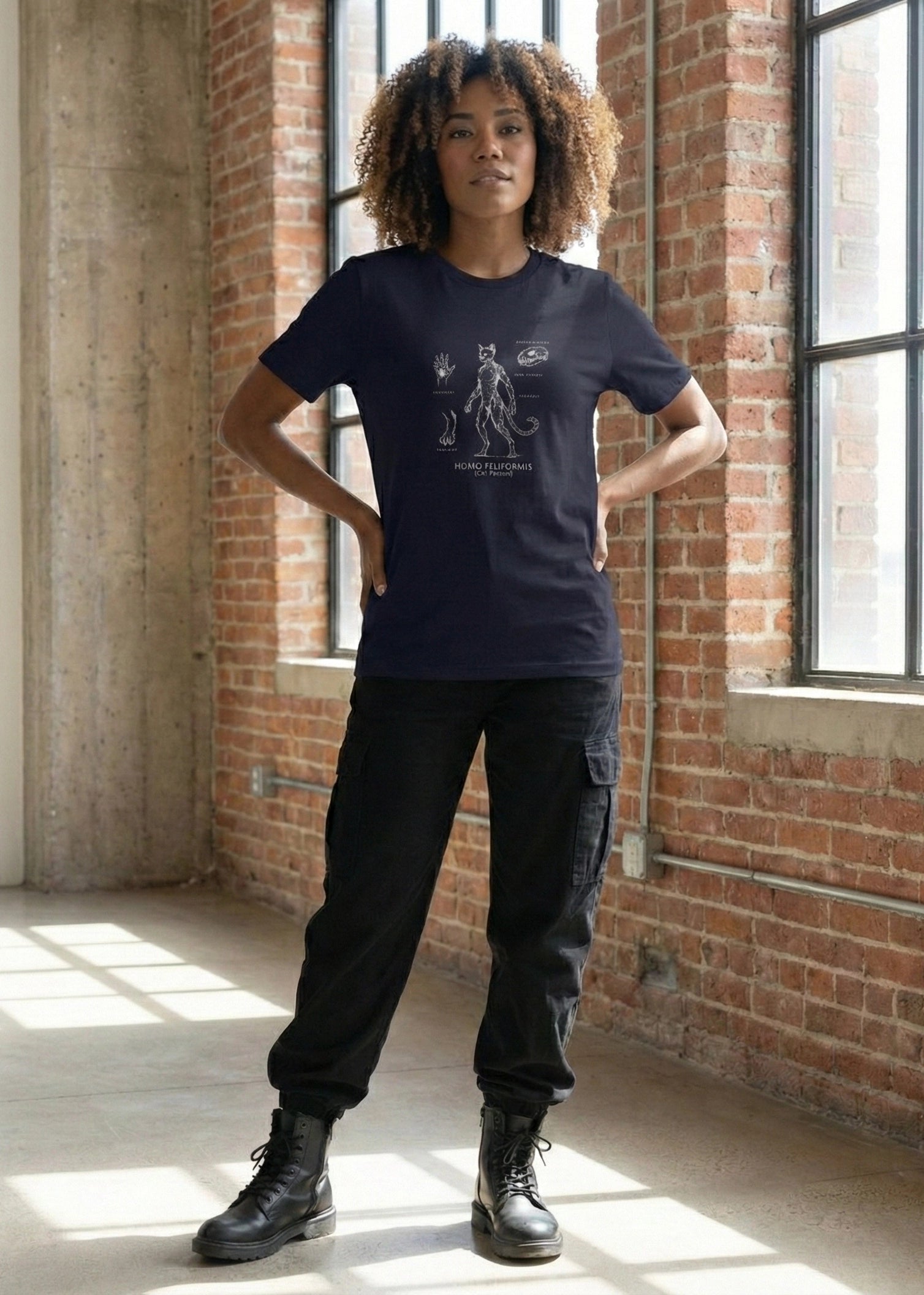Person wearing a black t-shirt with a graphic design in a room with brick walls and large windows.