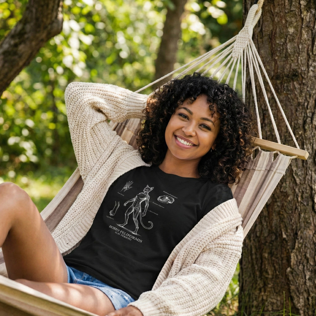 Woman sitting in a hammock outdoors wearing a black t-shirt with graphics.