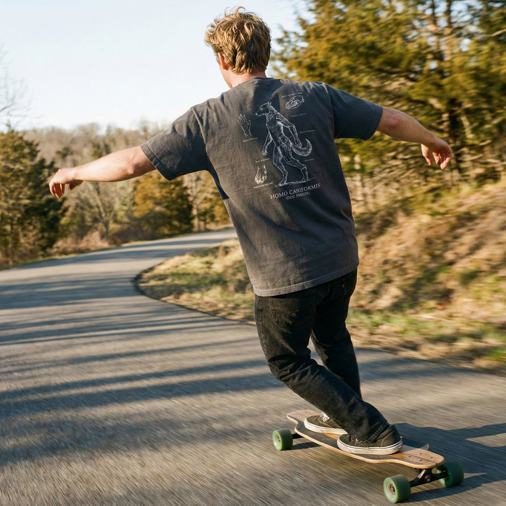Person skateboarding on a paved road with trees in the background