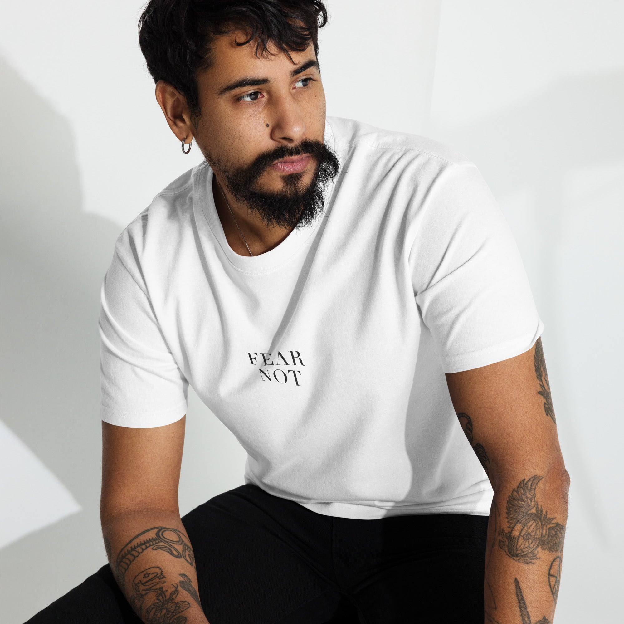 Man wearing a white t-shirt with 'FEAR NOT' text on a light background