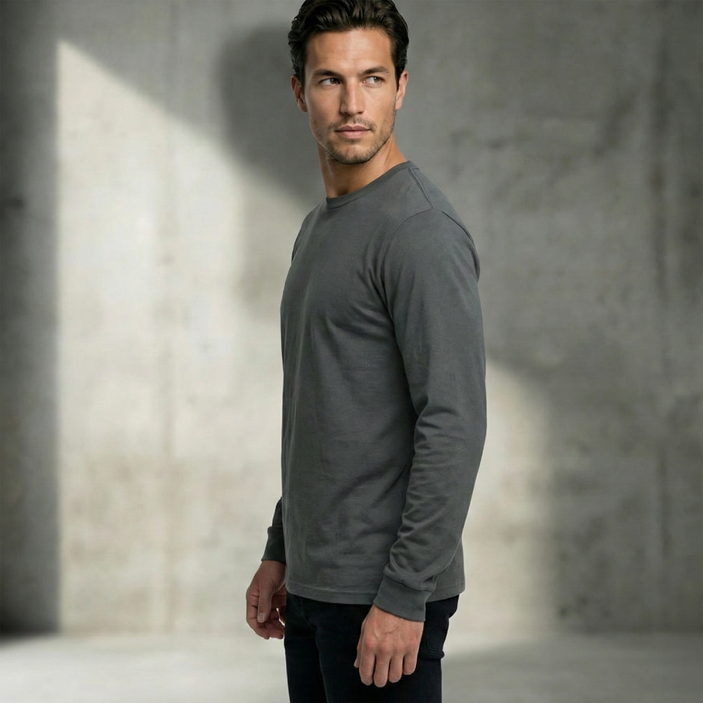 Man wearing a gray 185gsm organic cotton long-sleeve shirt standing against a textured wall