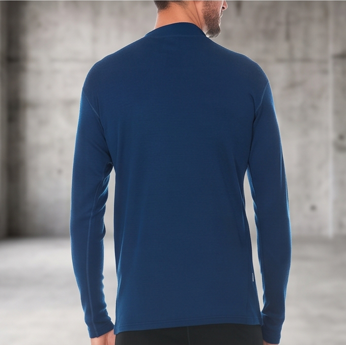 A man wearing a blue 100 percent merino wool mock neck shown from the back against a textured grey background.