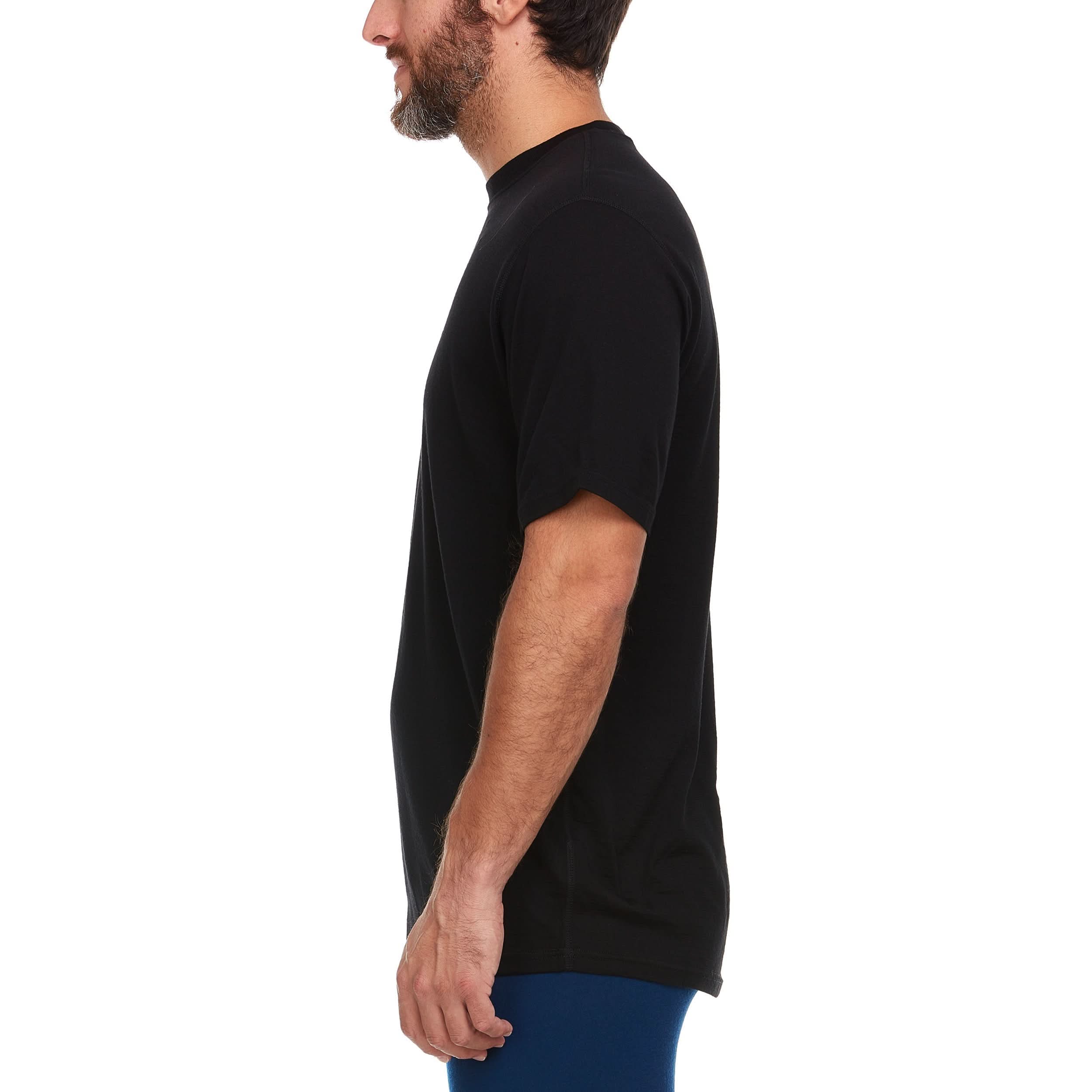 A man wearing a black 100 percent merino wool t shirt shown from the side against a solid white background.