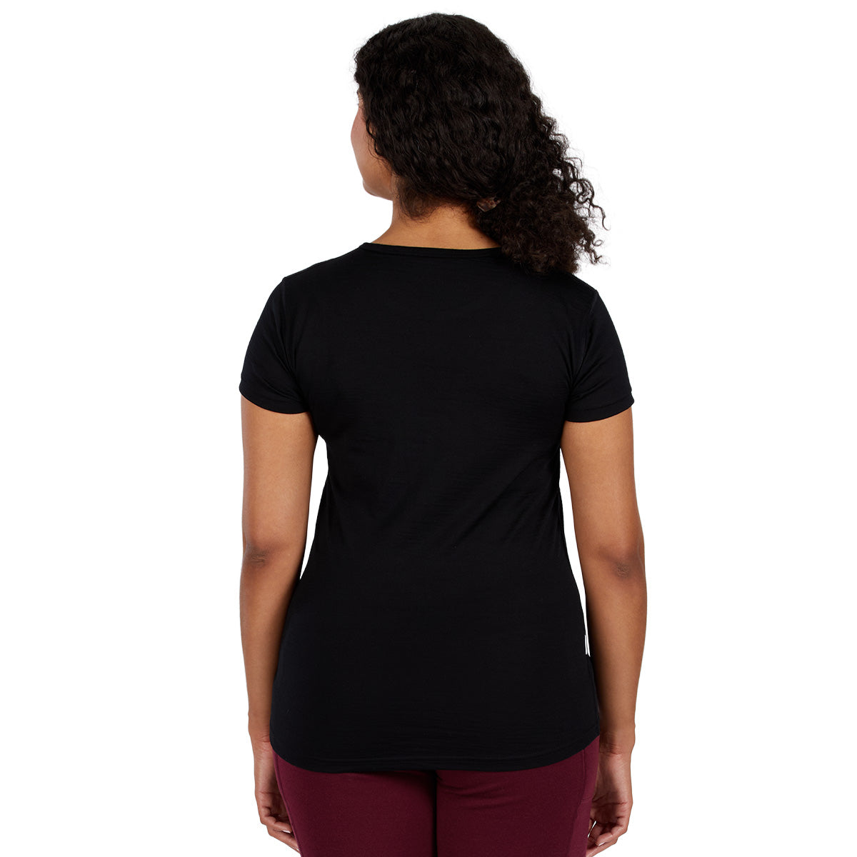 A woman wearing a black 100 percent merino wool t shirt shown from the back against a solid white background.