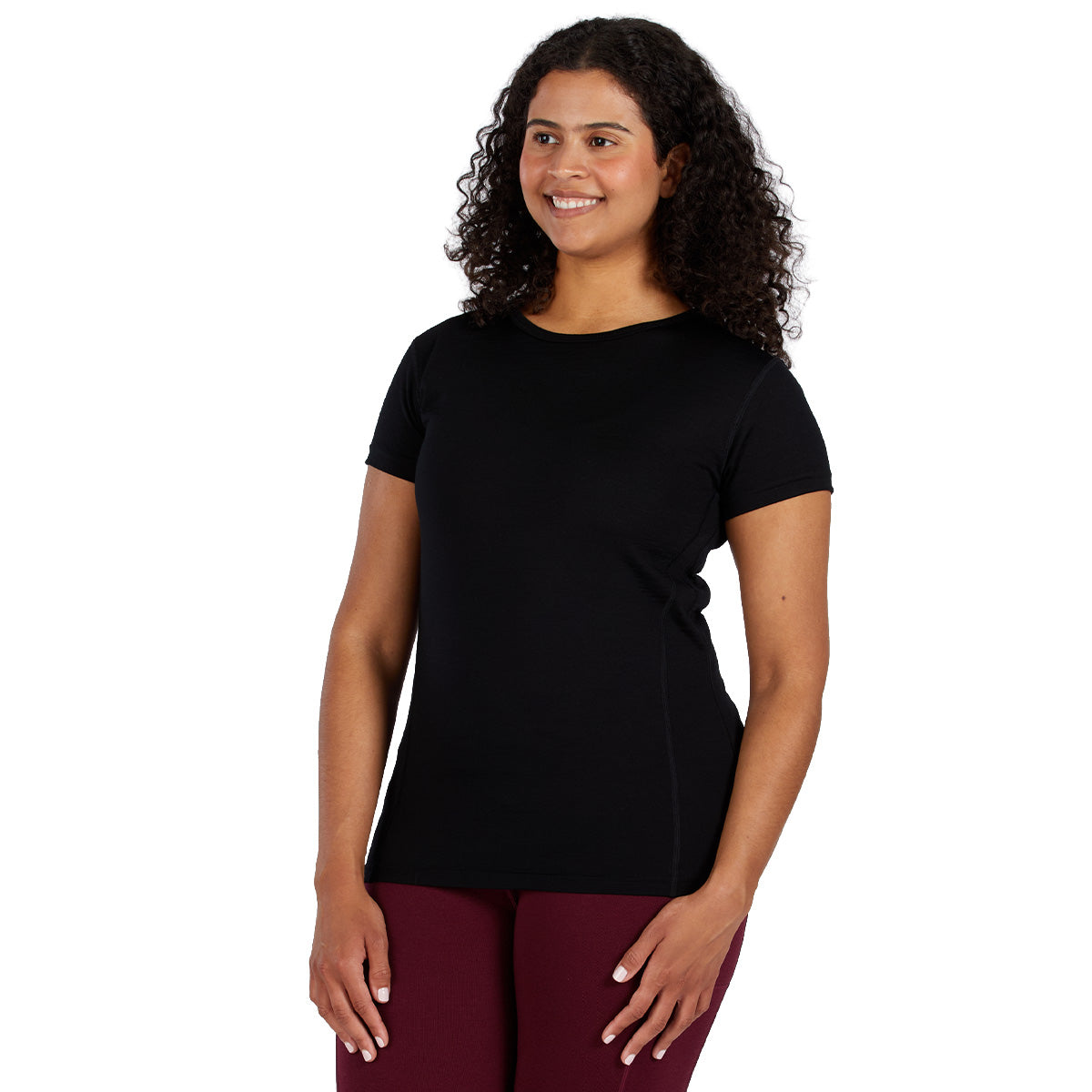 A woman wearing a black 100 percent merino wool t shirt shown from the waist up against a solid white background.