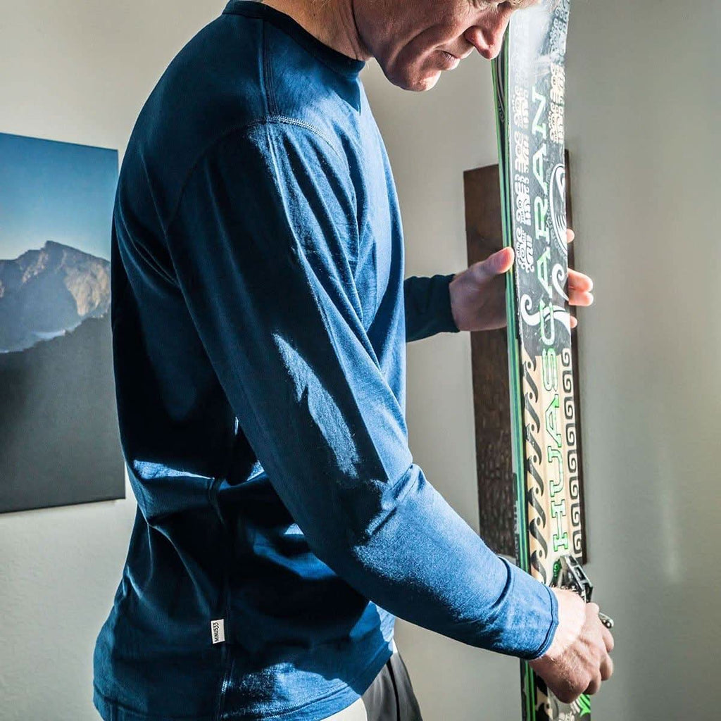 Mean wearing a blue 100% merino wool base layer holding a snowboard