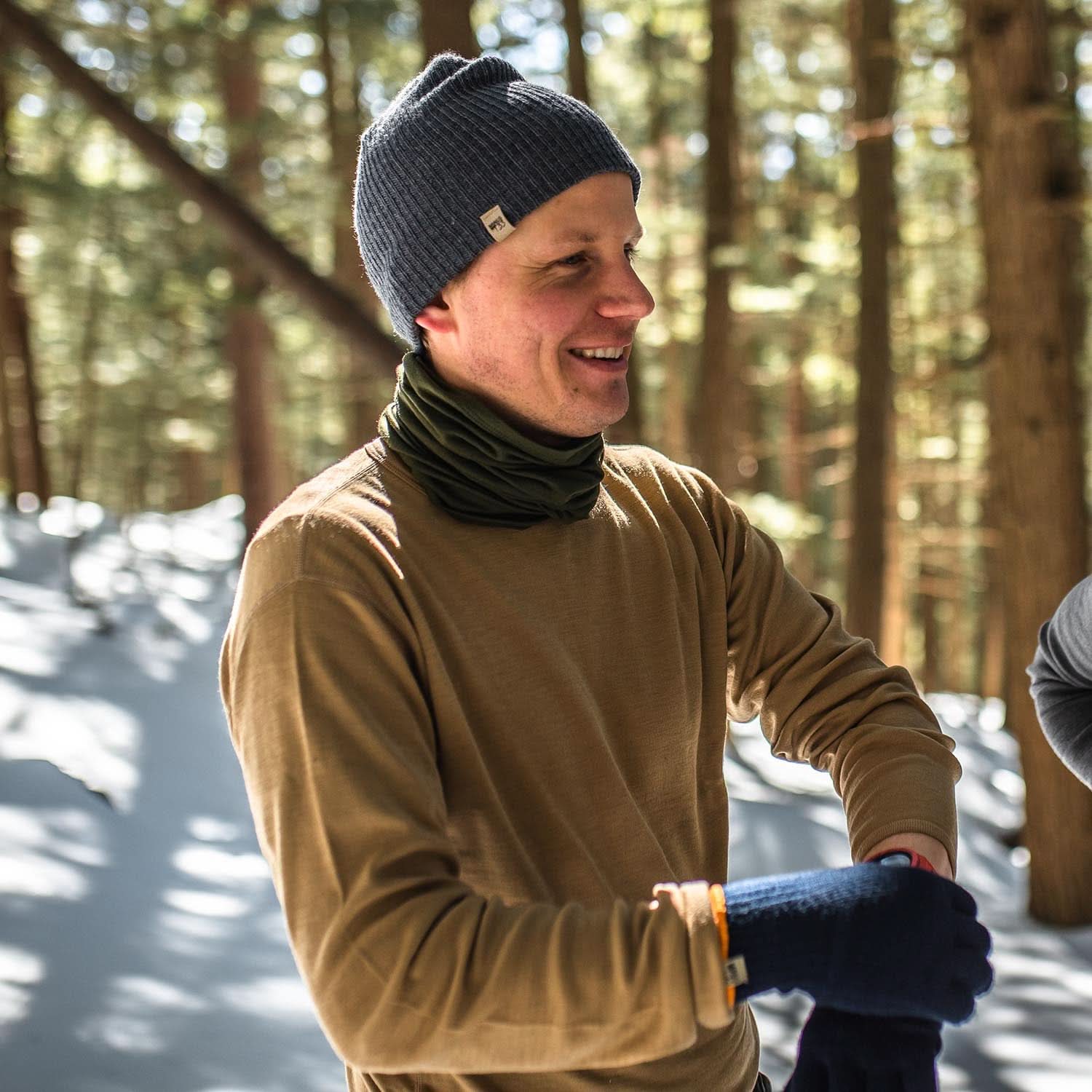 Man wearing a Desert Sand 100% merino wool base layer top in a snowy forest
