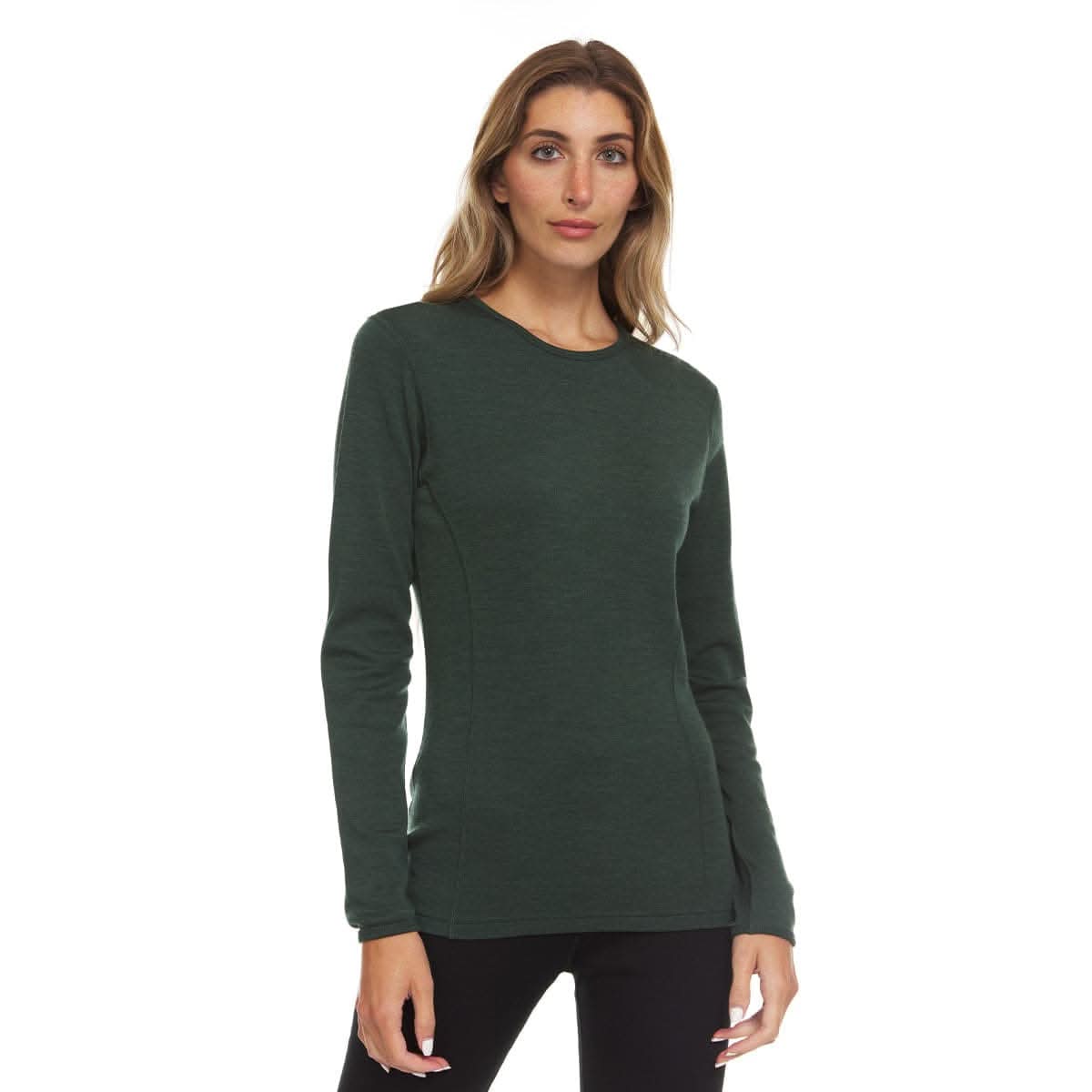 A woman modeling a dark forest green long-sleeve crewneck 100 percent merino wool base layer knit top against a plain white background.