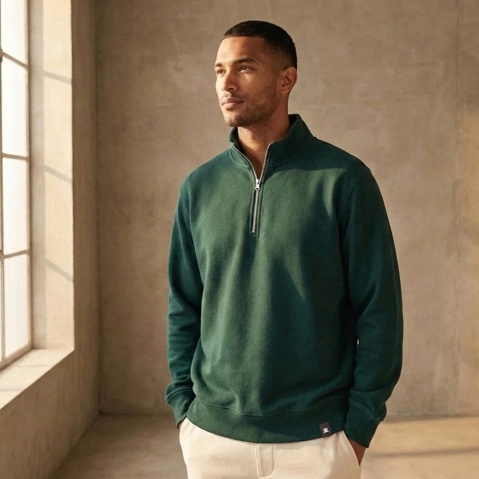 Man wearing a green organic cotton quarter-zip sweatshirt in a room with a window.