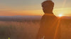 man in sunglasses wears 500 gsm organic cotton quarter-zip sweatshirt against a panoramic view and striking sunset atop Burger Hill  in the hudson valley