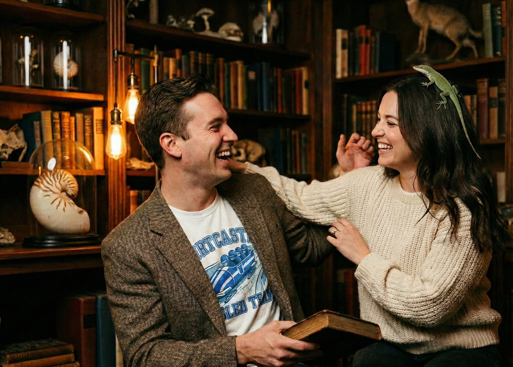 Man and woman sitting together in a cozy antique library with bookshelves and decorative curiosities.