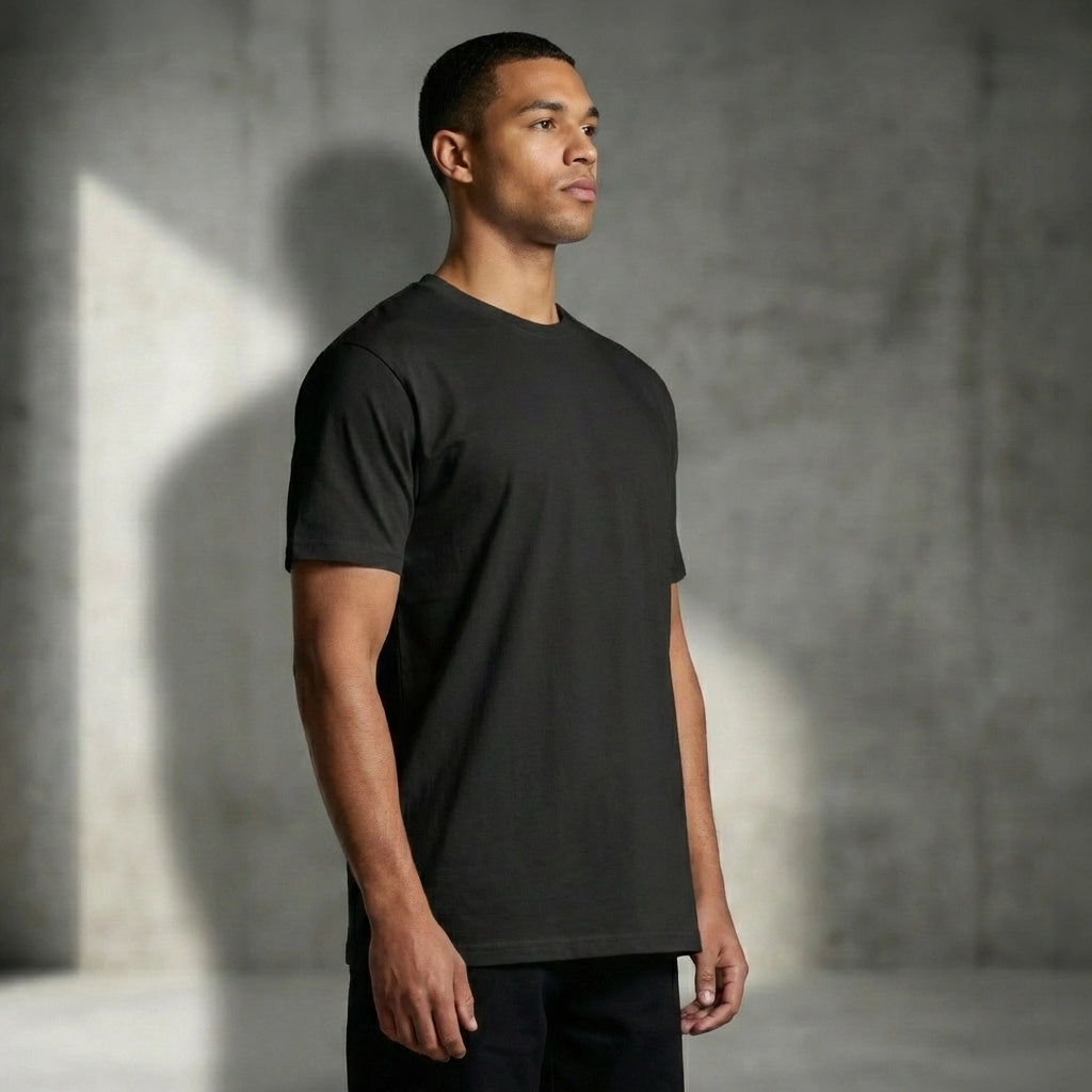 Man wearing a black t-shirt against a gray concrete wall